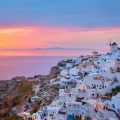 Oia village with traditional white houses and windmills in Santorini island on sunset in twilight, Greece