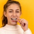 A girl puts a clear aligner into her mouth.