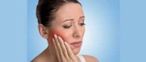 A woman with tooth pain clutches her face.