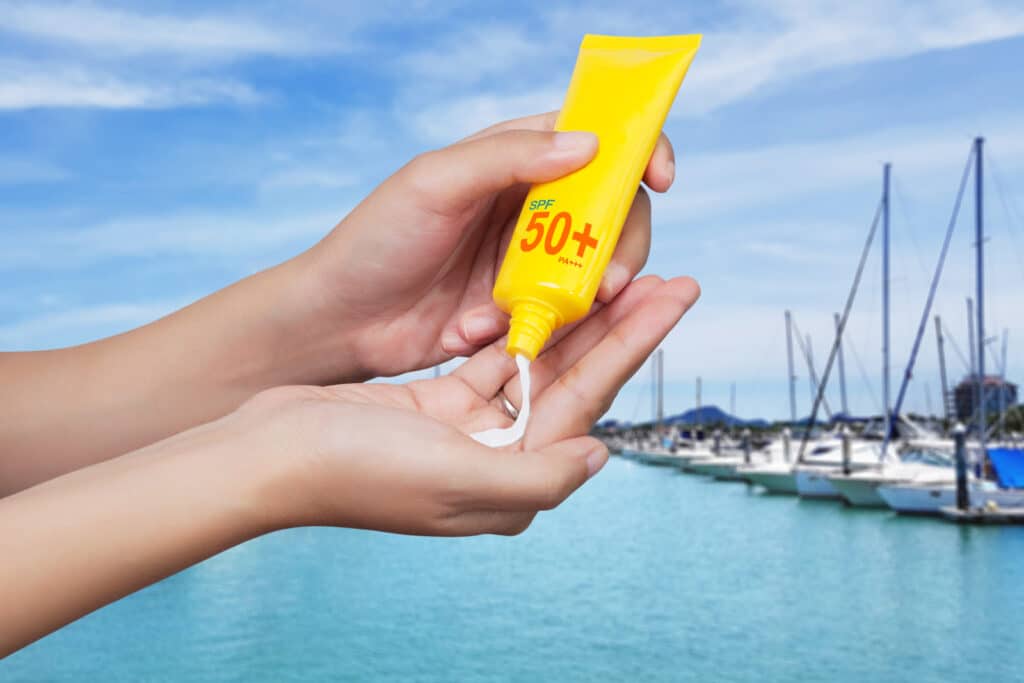 A person applying sunscreen outdoors on a sunny day