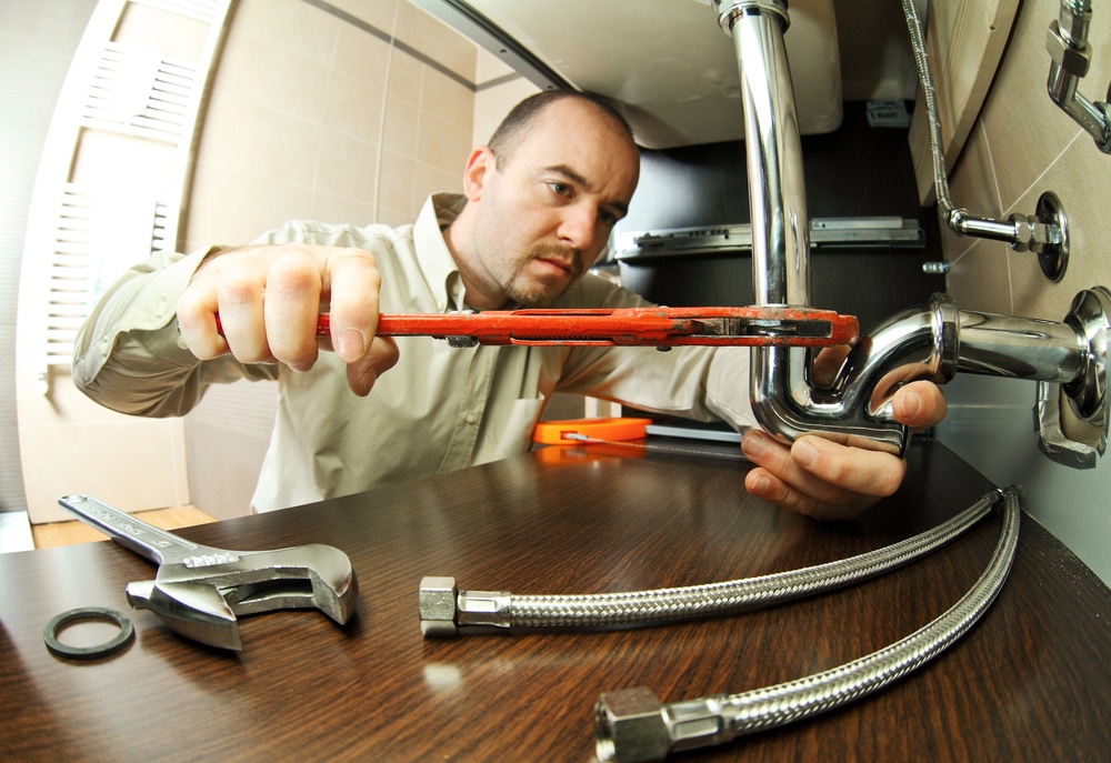 A plumber works on repairing a pipe.