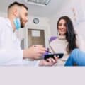 An orthodontist shows an X-ray photo on his phone to a female patient.