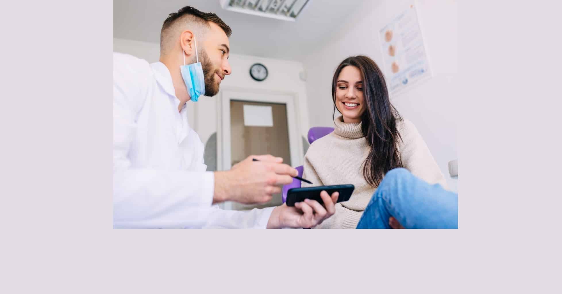 An orthodontist shows an X-ray photo on his phone to a female patient.