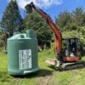 digger carrying septic tank on farm in Hamilton
