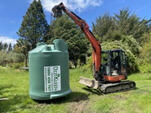 digger carrying septic tank on farm in Hamilton