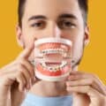 An orthodontist holds a model of a jaw with braces.