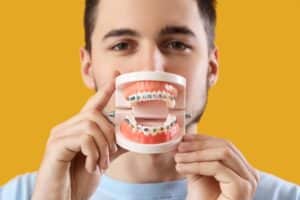 An orthodontist holds a model of a jaw with braces.