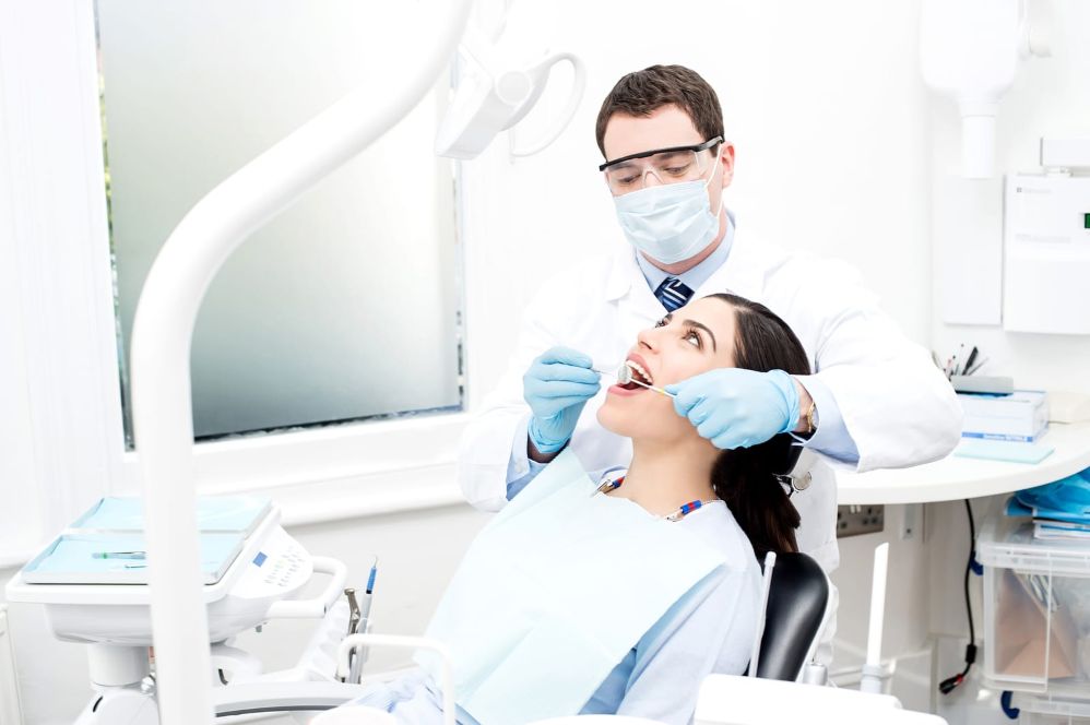 An orthodontist examines a patient's teeth at his clinic.
