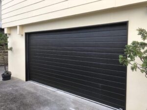 black garage door on cream house Auckland