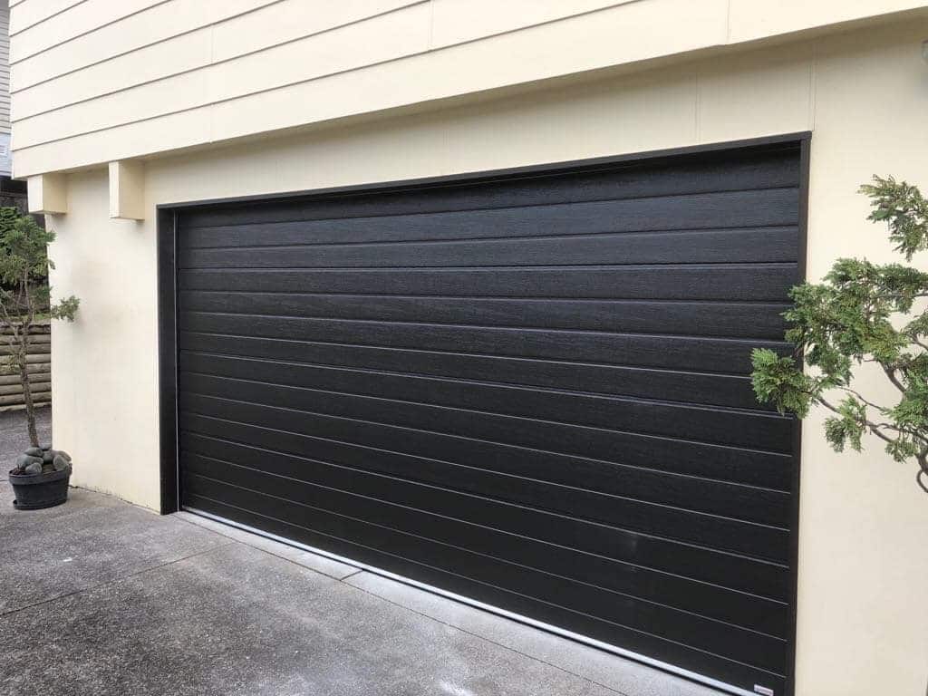black garage door on cream house Auckland