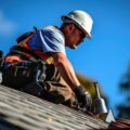 An experienced roofing specialist installing a metal roof under a clear blue sky.