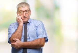 A worried middle-aged landlord thinking about rental compliance and legal risks in property management.